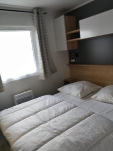 2 łóżka pojedyncze w sypialni z oknem w obiekcie mobilhome 3 chambres w mieście Litteau