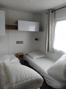 twee bedden in een kamer met een raam bij mobilhome 3 chambres in Litteau