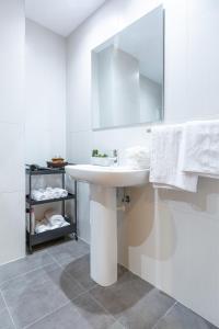 Baño blanco con lavabo y espejo en Unamuno by Bilbao Living, en Bilbao