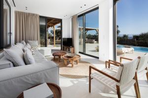 een woonkamer met een witte bank en stoelen bij Villa al Sur in Chania