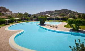 a large swimming pool with chairs in a resort at Chia Laguna - Hotel Village in Chia