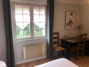 a bedroom with a bed and a desk and a window at Logis Hotel De La Corniche in Brest