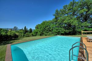 une piscine bleue avec une terrasse en bois dans l'établissement Casale Giotto by PosarelliVillas, à Vicchio