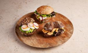 three sandwiches on a wooden plate on a table at RM The Experience - Small Portuguese Hotels in Setúbal