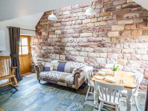 a living room with a couch and a brick wall at Jacob's Barn in Wootton