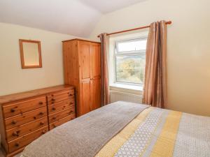 a bedroom with a bed and a dresser and a window at Pine Cottage in Bakewell