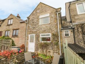a stone house with a table and chairs in front of it at Pine Cottage in Bakewell