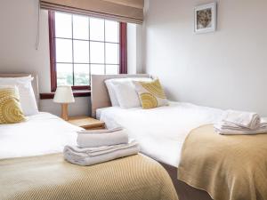 two twin beds in a room with a window at Sea Lily in Cheswick