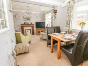 a living room with a table and chairs and a television at Bumble Bee Cottage in Skegness