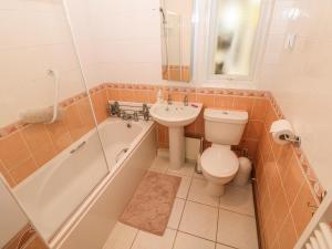 a bathroom with a sink and a toilet and a bath tub at Bumble Bee Cottage in Skegness +14 photos