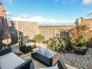 a patio with chairs and a table and a fence at Bumble Bee Cottage in Skegness
