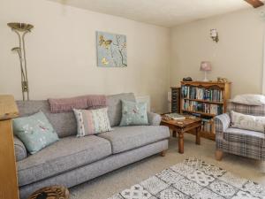 a living room with a gray couch and a table at Megs Cottage in Norwich