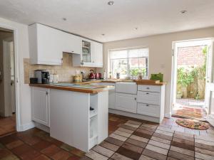 cocina con armarios blancos y encimera en Megs Cottage en Norwich