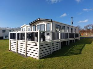 a house with a white fence in the grass at Bude Coastal Lodge in Bude