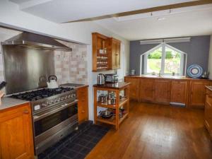 uma cozinha com um fogão, pisos em madeira e uma janela em Corner Cottage em Reynoldston