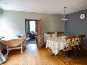 a living room with a table and chairs and a kitchen at Corner Cottage, Swansea in Reynoldston