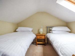 um quarto com duas camas e uma mesa com um candeeiro em Corner Cottage em Reynoldston