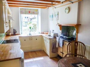 a kitchen with white cabinets and a table and a window at The Green in Lastingham