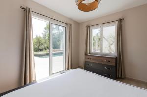 a bedroom with a bed and a large window at Superbe Villa Seillans LA GRANDE BASTIDE avec piscine, jardin, climatisation et salle de sport in Seillans