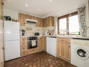 a kitchen with white appliances and wooden cabinets at Pond End Cottage in Morland