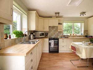 a kitchen with white cabinets and a sink and a table at Shepherds Rest in Warbstow