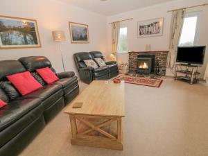 a living room with a couch and a table and a fireplace at Orchard End in Boyton