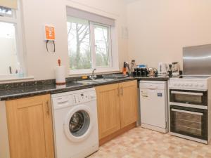 una cucina con lavatrice e lavandino di Orchard End a Boyton