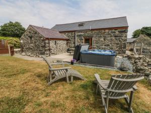 a stone cottage with two chairs and a hot tub at Sgubor in Chwilog