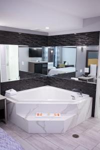 a large white bath tub in a room with a bedroom at Travelodge Inn & Suites by Wyndham West Covina in West Covina