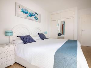 Un dormitorio blanco con una gran cama blanca con almohadas azules. en Apartment Cofisa-2 by Interhome, en Jávea