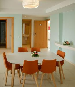 a dining room with a white table and orange chairs at Zephyr Agadir in Agadir