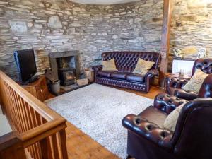 a living room with leather furniture and a stone wall at Horrace Farm Cottage in Pennington