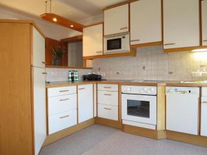 cocina con armarios blancos y microondas en Apartment Liftblick - NKI190 by Interhome, en Neukirchen am Großvenediger
