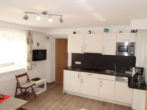 a kitchen with white cabinets and a black counter top at Apartment Leni - FIE150 by Interhome in Fliess