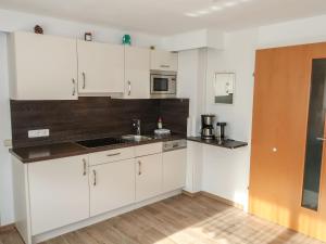 una cocina con armarios blancos y fregadero en Apartment Leni - FIE150 by Interhome, en Fliess