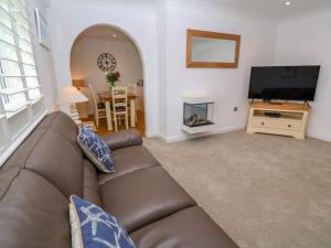 a living room with a brown couch and a fireplace at Holywell Bay View in Newquay