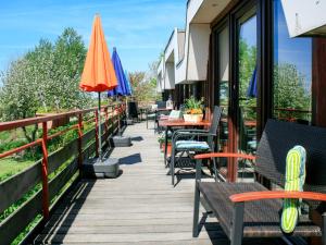 una terrazza con tavoli, sedie e ombrelloni di Apartment Nordsee-Ferienhaus-1 by Interhome a Friedrichskoog