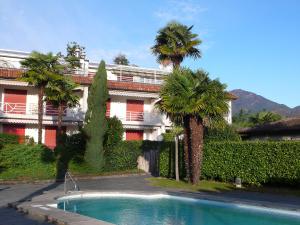 a building with palm trees and a swimming pool at Apartment Collina Verde B by Interhome in Ascona
