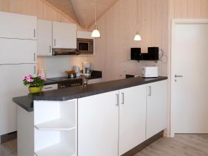 a kitchen with white cabinets and a black counter top at Holiday Home Holiday Vital Resort - GBE122 by Interhome in Großenbrode +22 photos