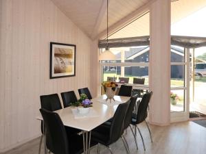 a dining room with a white table and black chairs at Holiday Home Holiday Vital Resort - GBE122 by Interhome in Großenbrode