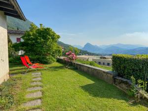 una sedia rossa seduta sull'erba in un cortile di Holiday Home Cityview Lugano - Casa Carlo by Interhome a Cadro