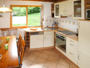 サシュラングにあるHoliday Home Chalet Walchsee by Interhomeの白いキャビネットと木製テーブル付きのキッチン