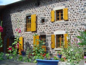 ein Steingebäude mit gelben Fenstern und Blumen in der Unterkunft Holiday Home ferme by Interhome in Agizoux