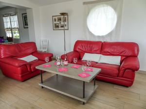Plobannalec-LesconilにあるHoliday Home Sables Blancs by Interhomeのリビングルーム(赤いソファ、ワイングラス付きのテーブル付)