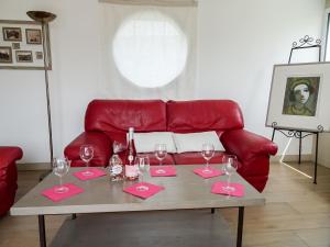 a table with wine glasses and a red couch at Holiday Home Sables Blancs by Interhome in Plobannalec-Lesconil
