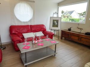 Plobannalec-LesconilにあるHoliday Home Sables Blancs by Interhomeのリビングルーム(赤いソファ、テーブル付)