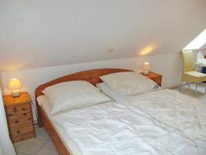 een slaapkamer met een bed met witte lakens en kussens bij Apartment Gartenstraße-2 by Interhome in Ostseebad Karlshagen