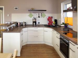 a kitchen with white cabinets and a wooden floor at Holiday Home Johannika by Interhome in Godern