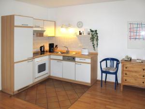 a kitchen with white cabinets and a blue chair at Apartment Juliusruh-3 by Interhome in Juliusruh