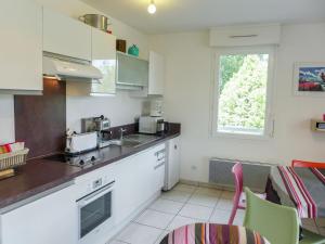 une cuisine avec des placards blancs et une table avec des chaises dans l'établissement Apartment Les Demeures de Brindos by Interhome, à Anglet